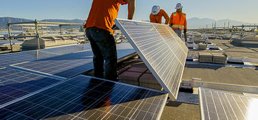 Three workers install solar panels