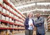 Two team members in a warehouse smiling at the camera